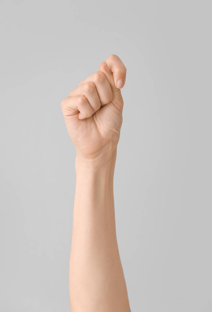 Hand showing letter T on grey background. Sign language alphabet - Foto, imagen