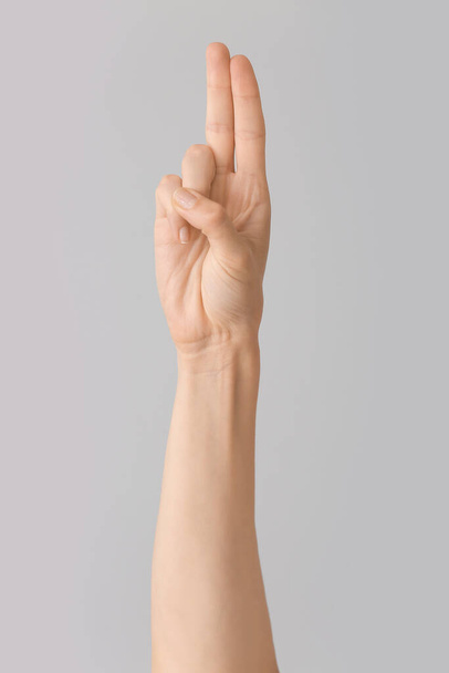 Hand showing letter U on grey background. Sign language alphabet - 写真・画像