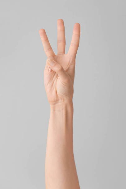 Käsi näyttää kirjaimen W harmaalla taustalla. Viittomakielen aakkoset - Valokuva, kuva