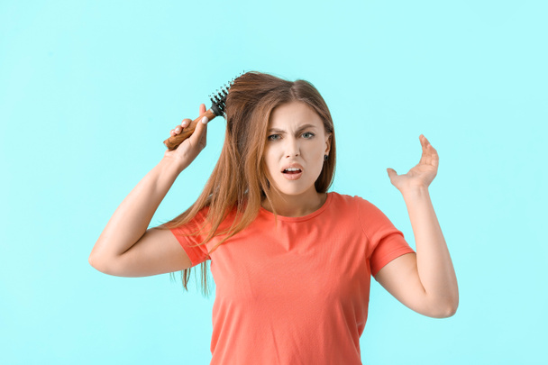 Mujer estresada cepillando el cabello sobre fondo de color - Foto, Imagen