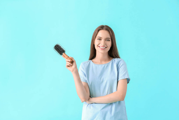 Young woman with hair brush on color background - Photo, Image