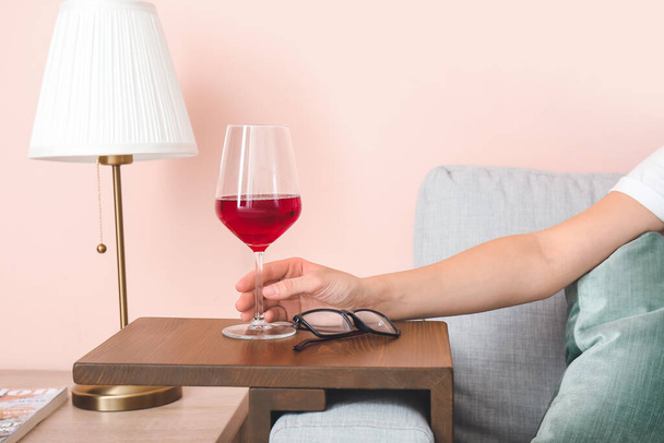 Vrouw met glas wijn rustend op de bank thuis - Foto, afbeelding