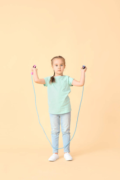 Cute little girl jumping rope against color background - Foto, Imagem