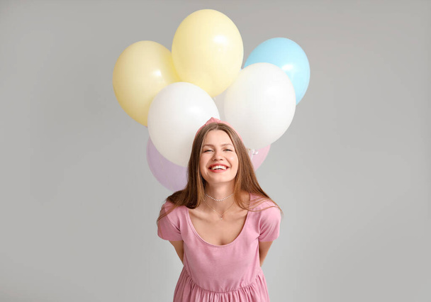 Nuori nainen, jolla on ilmapalloja harmaalla taustalla - Valokuva, kuva
