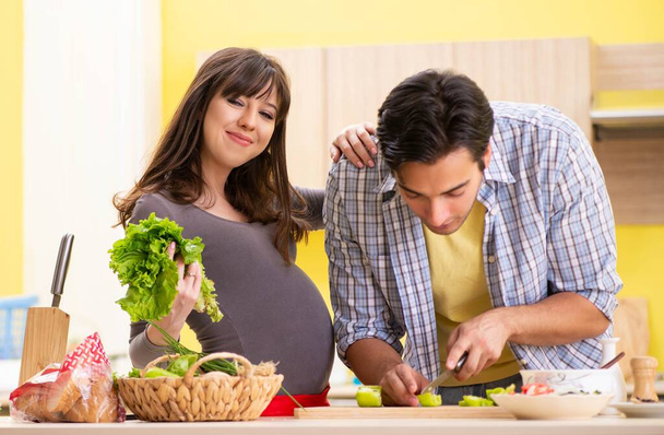 Erkek ve hamile kadın mutfakta salata hazırlıyorlar. - Fotoğraf, Görsel