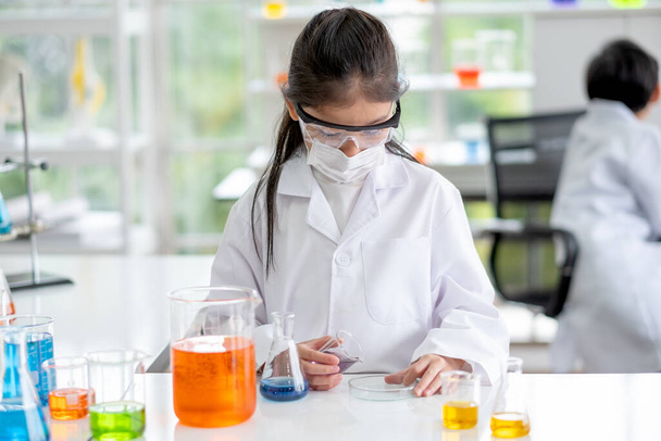 素敵な女の子は昼光と実験室で色の化学物質を調べるのをお楽しみください。子供のための科学の良い実践と教育の概念は、彼らの学習をサポートします. - 写真・画像