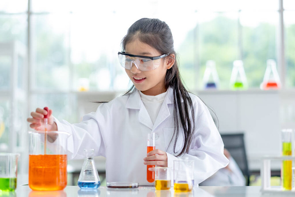 Sevimli küçük kız laboratuardaki renk kimyasallarını gün ışığında inceleyerek zevk alıyor ve heyecanlandırıyor. Çocuklar için iyi uygulama ve bilim eğitimi kavramı öğrenmelerini destekliyor. - Fotoğraf, Görsel