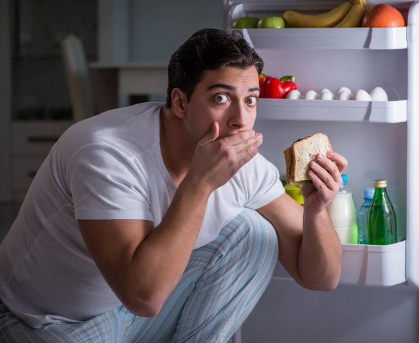 Man aan de koelkast 's nachts aan het eten - Foto, afbeelding