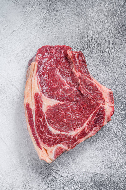 Steak de cow-boy cru ou côtelette sur l'os. Du bœuf en marbre. Fond gris. Vue du dessus. - Photo, image