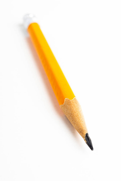 Um close-up ou macro tiro com foco seletivo de um clássico afiado amarelo-laranja toco lápis hexagonal definido em papel branco liso. - Foto, Imagem