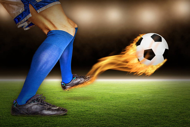 Soccer player kicking a fiery flaming football in flight at a stadium. - Photo, Image