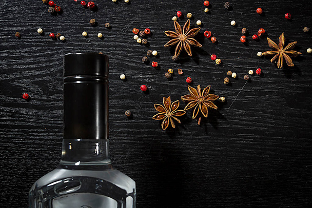 Bottle of anise vodka and spices on wooden black background - Photo, Image