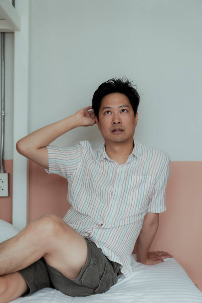 Azji gej w rozebrany koszula opierając się o w ściana i patrzeć w sufit. - Zdjęcie, obraz