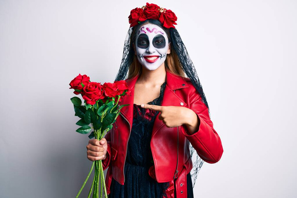 Femme portant le jour du costume mort tenant des roses souriant heureux pointant avec la main et le doigt  - Photo, image