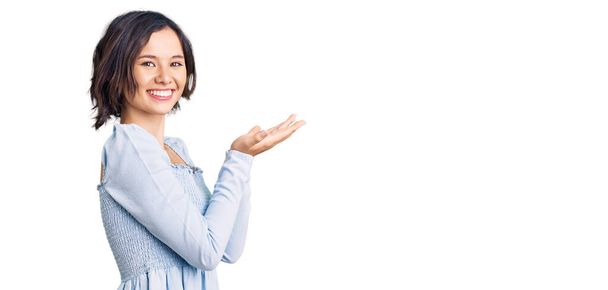 Młoda piękna dziewczyna w ubraniu casual wskazując na bok z dłońmi otwartymi dłońmi pokazując przestrzeń kopiowania, prezentując reklamę uśmiechnięty szczęśliwy podekscytowany  - Zdjęcie, obraz