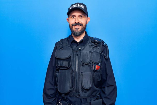 Nuori komea mies yllään poliisin univormu näyttää positiiviselta ja onnelliselta seisoo ja hymyilee luottavainen hymy näyttää hampaat  - Valokuva, kuva