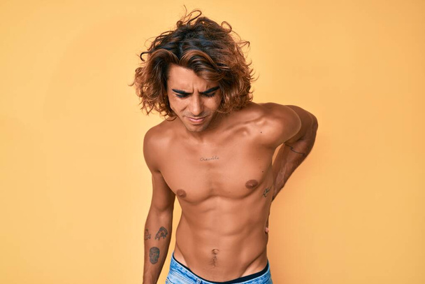 Nuori latinomies seisoo paidaton selkäkipu, koskettaa takaisin käsin, lihaskipu  - Valokuva, kuva