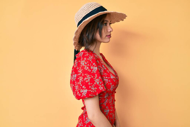 Fiatal gyönyörű lány visel nyári kalap látszó oldalra, pihenjen profil pózol természetes arc magabiztos mosollyal.  - Fotó, kép