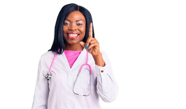 Doktor steteskop takan genç Afro-Amerikan kadın başarılı bir fikirle işaret ediyor. Heyecanlı ve mutlu. Bir numara..  - Fotoğraf, Görsel