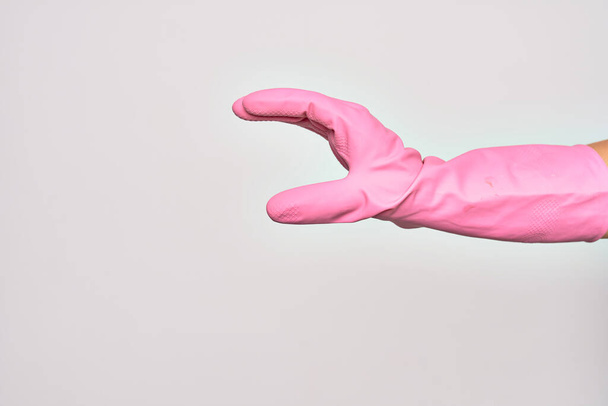 Mano della giovane donna caucasica che indossa un guanto di pulizia rosa facendo segno di cattura su sfondo bianco isolato - Foto, immagini