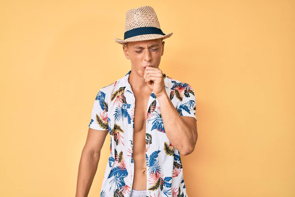 Menino hispânico jovem usando chapéu de verão sentindo-se mal e tosse como sintoma de frio ou bronquite. conceito de cuidados de saúde.  - Foto, Imagem