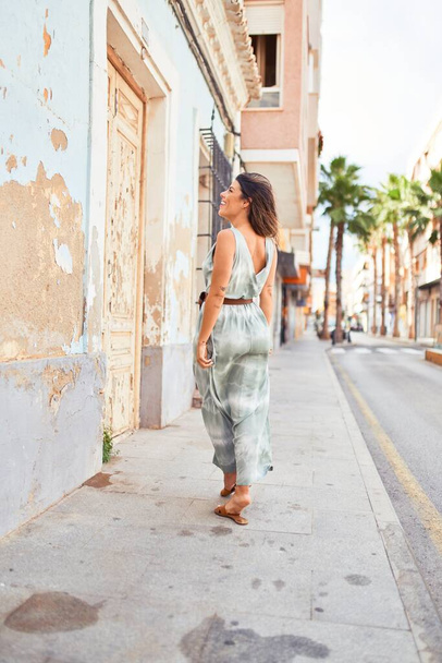 Beautiful young woman wearing fashionable clothes walking down the street - Fotó, kép