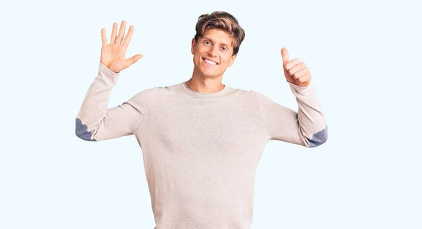Νεαρός όμορφος άντρας που φοράει καθημερινά ρούχα και δείχνει προς τα πάνω με τα δάχτυλα νούμερο έξι ενώ χαμογελά σίγουρος και χαρούμενος.  - Φωτογραφία, εικόνα