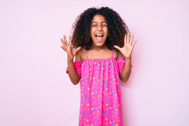 Kıvırcık saçlı Afro-Amerikalı çocuk başarıyı kutlamak için çılgın ve çılgınca giyinmiş kollarını kaldırmış ve gözlerini kapatmış heyecanlı çığlıklar atıyordu. Kazanan konsept  - Fotoğraf, Görsel