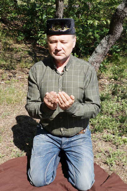 ένας άνθρωπος εκτελεί προσευχή στα γόνατά του στη φύση - Φωτογραφία, εικόνα