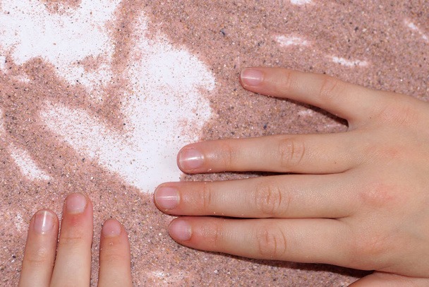 αμμοθεραπεία, δύο χέρια σχέδιο με ροζ άμμο σε ένα λευκό τραπέζι. - Φωτογραφία, εικόνα