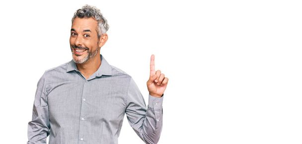 Middle age grey-haired man wearing casual clothes showing and pointing up with finger number one while smiling confident and happy.  - Photo, Image