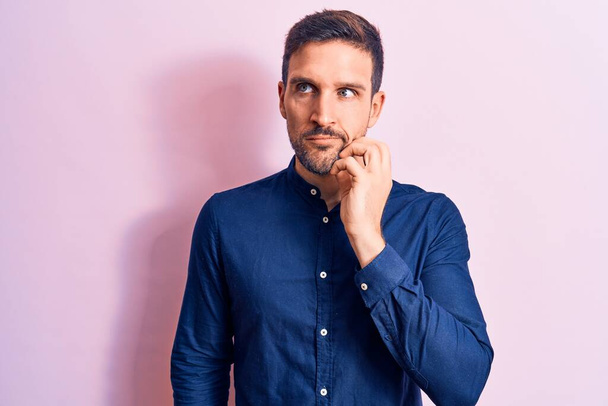 Young handsome man wearing casual shirt standing over isolated pink background thinking concentrated about doubt with finger on chin and looking up wondering - Foto, immagini