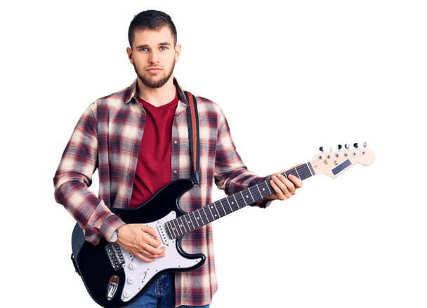 Junger gutaussehender Mann mit E-Gitarre und nüchternem Gesichtsausdruck, der selbstbewusst wirkt  - Foto, Bild