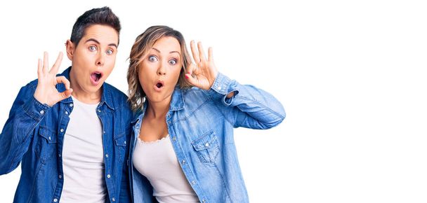 Couple de femmes portant des vêtements décontractés regardant surpris et choqué faisant ok symbole d'approbation avec les doigts. expression folle  - Photo, image
