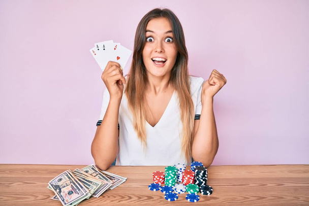 Güzel beyaz kadın poker oynuyor gururla bağırıyor, zaferi kutluyor ve kollarını kaldırarak çok heyecanlanıyor.  - Fotoğraf, Görsel