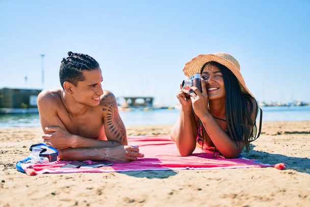 Jovem casal latino fazer foto usando a câmera vintage na praia. - Foto, Imagem