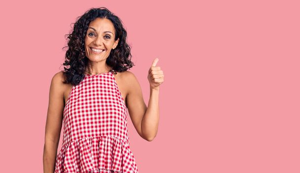 Middle age beautiful woman wearing casual sleeveless t shirt smiling happy and positive, thumb up doing excellent and approval sign  - Photo, Image