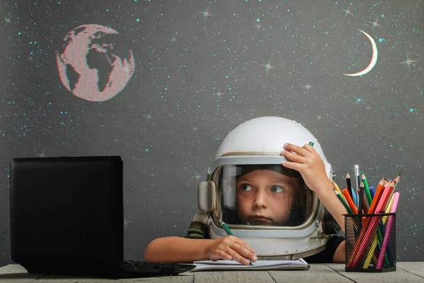 el niño estudia remotamente en la escuela, usando un casco de astronauta. de vuelta a la escuela. efectos fallo técnico - Foto, imagen