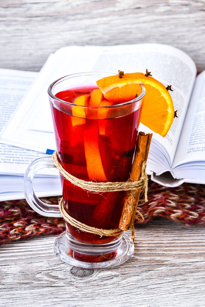 Mulled wine Hot christmas drink with spices on wooden background. Orange slice, cinnamon sticks, books and sweater. Christmas morning. Holiday atmosphere, Rustic style. The idea for creating greeting cards. Autumn beverage - Photo, Image