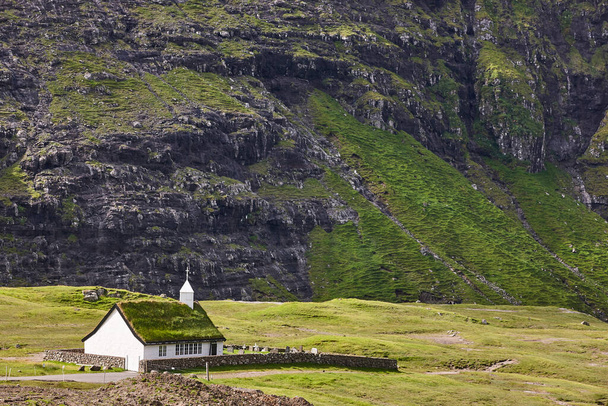 Зеленый пейзаж Фарерских островов. Село Саксун с живописной белой церковью - Фото, изображение