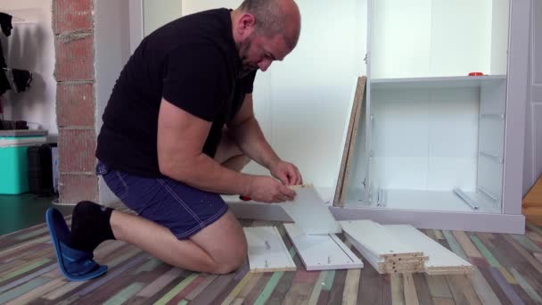μεσήλικας άνθρωπος συναρμολόγηση επίπλων στο σαλόνι στο σπίτι, με διάφορα εργαλεία - Πλάνα, βίντεο