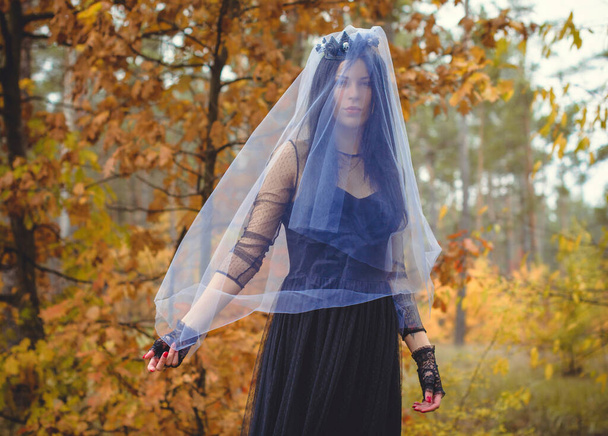 Halloween-Hexe in einem dunklen Wald. Schöne junge Frau in modernem Hexenkleid. Gestaltung von Halloween-Kunst. Dunkles Thema für Halloween-Konzept - Foto, Bild