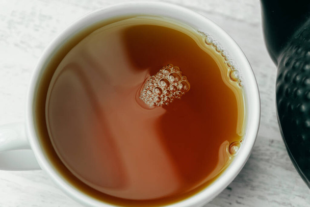 Foto da vicino di una tazza di tè nero fresco sul tavolo bianco - Foto, immagini