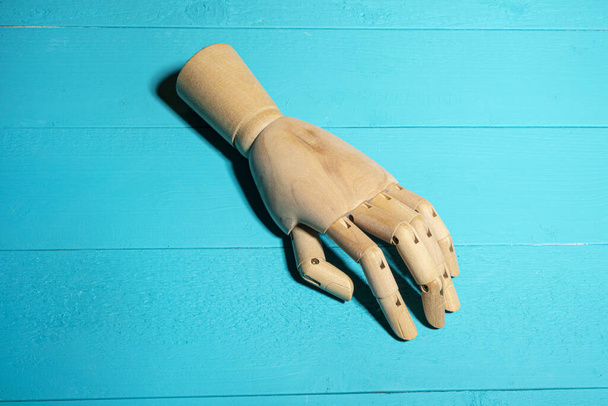 A wooden hand on a blue table - Foto, Imagen