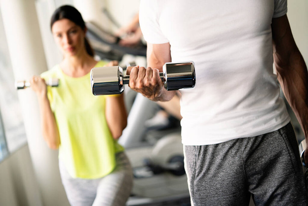 Sport, fitness, lifestyle and people concept. Group of happy poeple flexing muscles with dumbbells in gym - Fotoğraf, Görsel