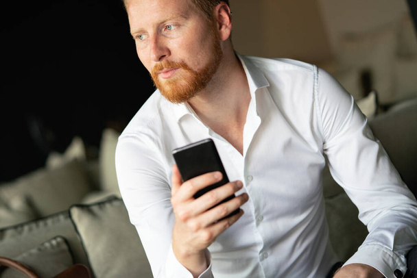 Portrait of handsome young businessman on a phone in the office - Photo, Image