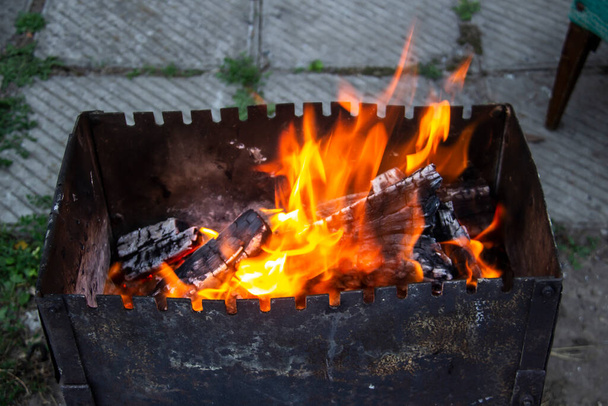 Barbecue grill mangal preparation with roaming fire outside building. Burns a firewood - Photo, Image