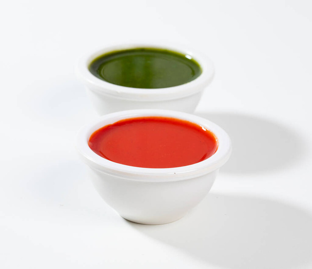 Red Hot Chilli Sauce mit grüner Chilisoße auf weißem Hintergrund - Foto, Bild