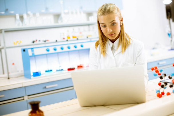 Cute kobieta badaczka w białym fartuchu laboratoryjnym za pomocą laptopa podczas pracy w laboratorium - Zdjęcie, obraz
