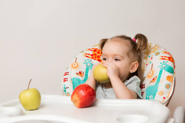 Foto de uma linda e alegre menina com tranças sentadas em uma cadeira de mesa de alimentação alta e fazendo caretas - Foto, Imagem
